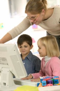 Teacher Helping Children Use Computer